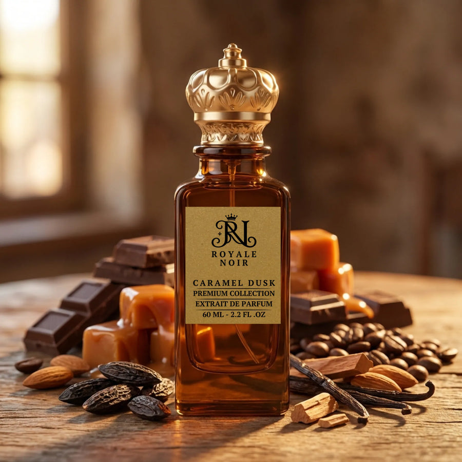 Perfume bottle labeled 'Royale Noir Caramel Dusk' The bottle has an gold cap. Surrounding it are various ingredients, including chocolate pieces, almonds, coffee beans, vanilla pods, and caramel. The composition conveys a warm, sweet, and rich fragrance.